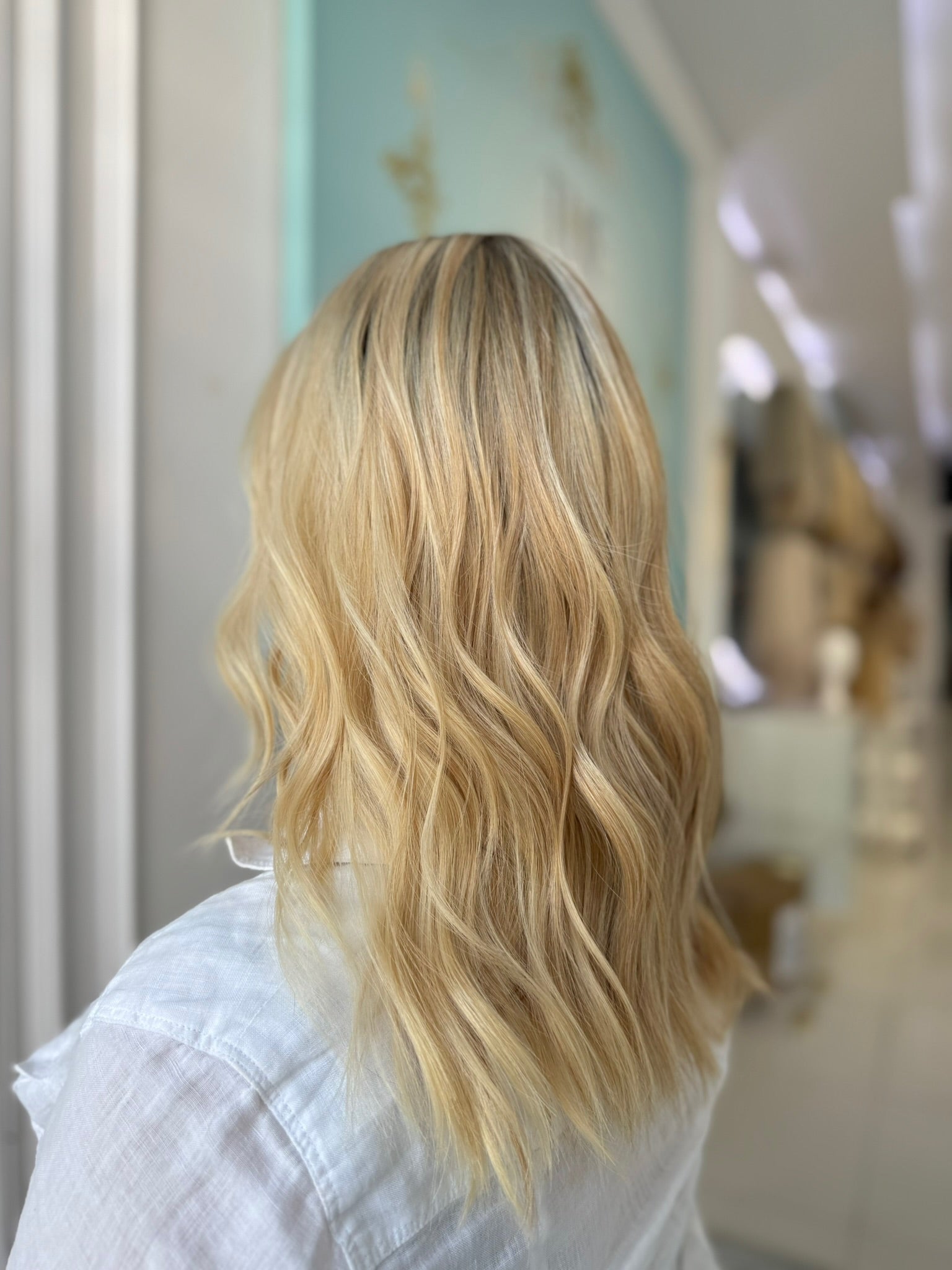 Side angle of model showcasing the layered waves and seamless lace front of the blonde Katie wig in blonde