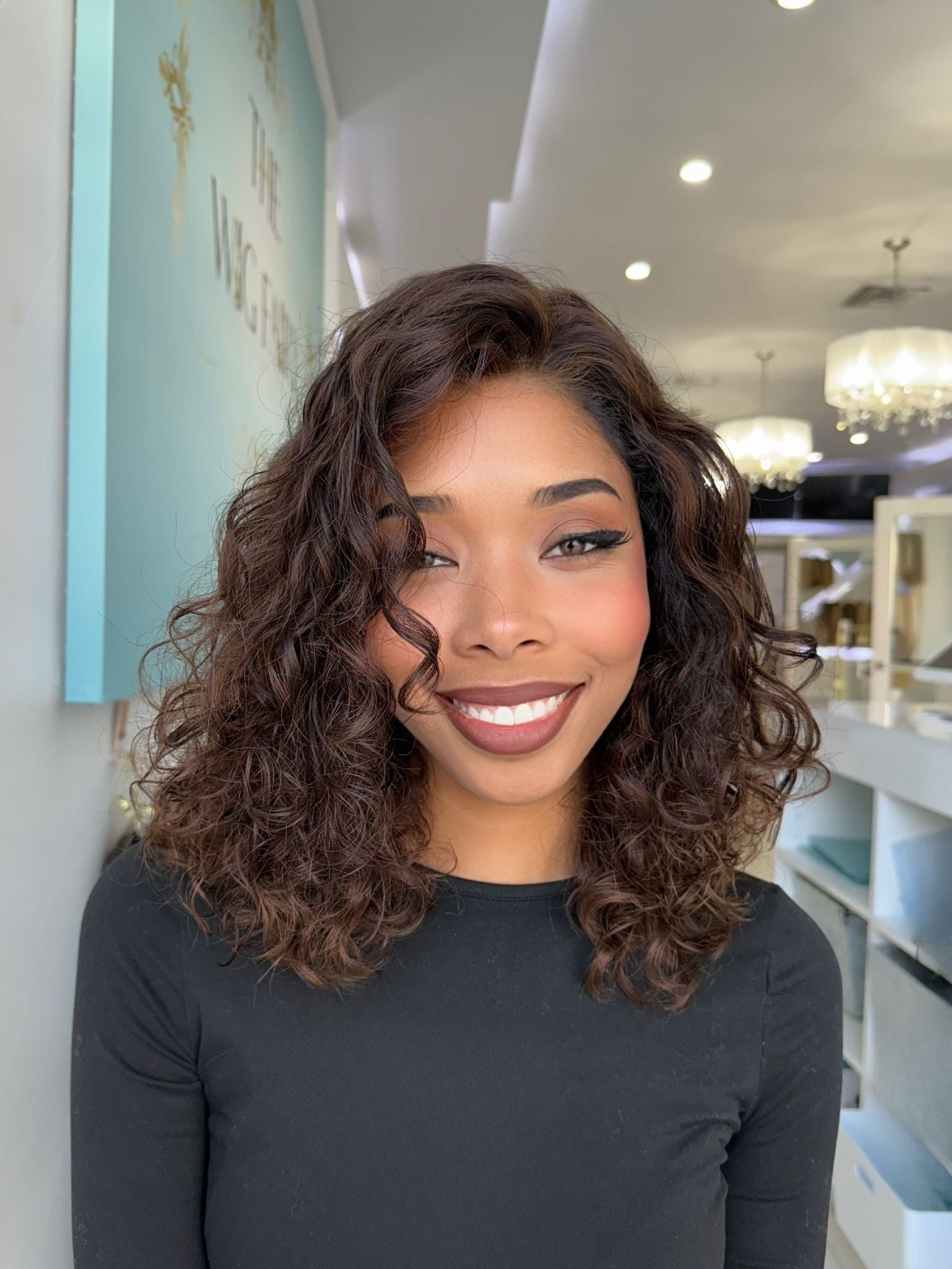 Marissa 17-inch curly human hair wig with soft caramel highlights worn by smiling woman