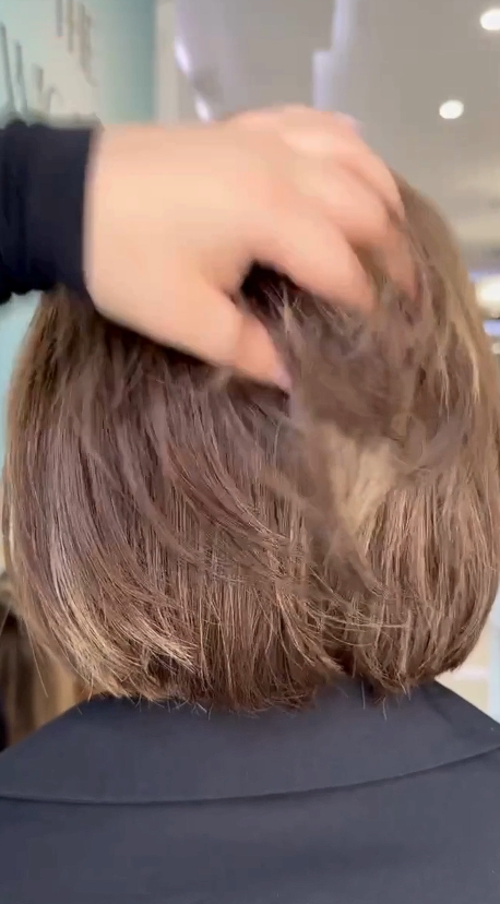 Video of a short, trendy brown wig with warm highlights, showing its layered cut and natural bounce.