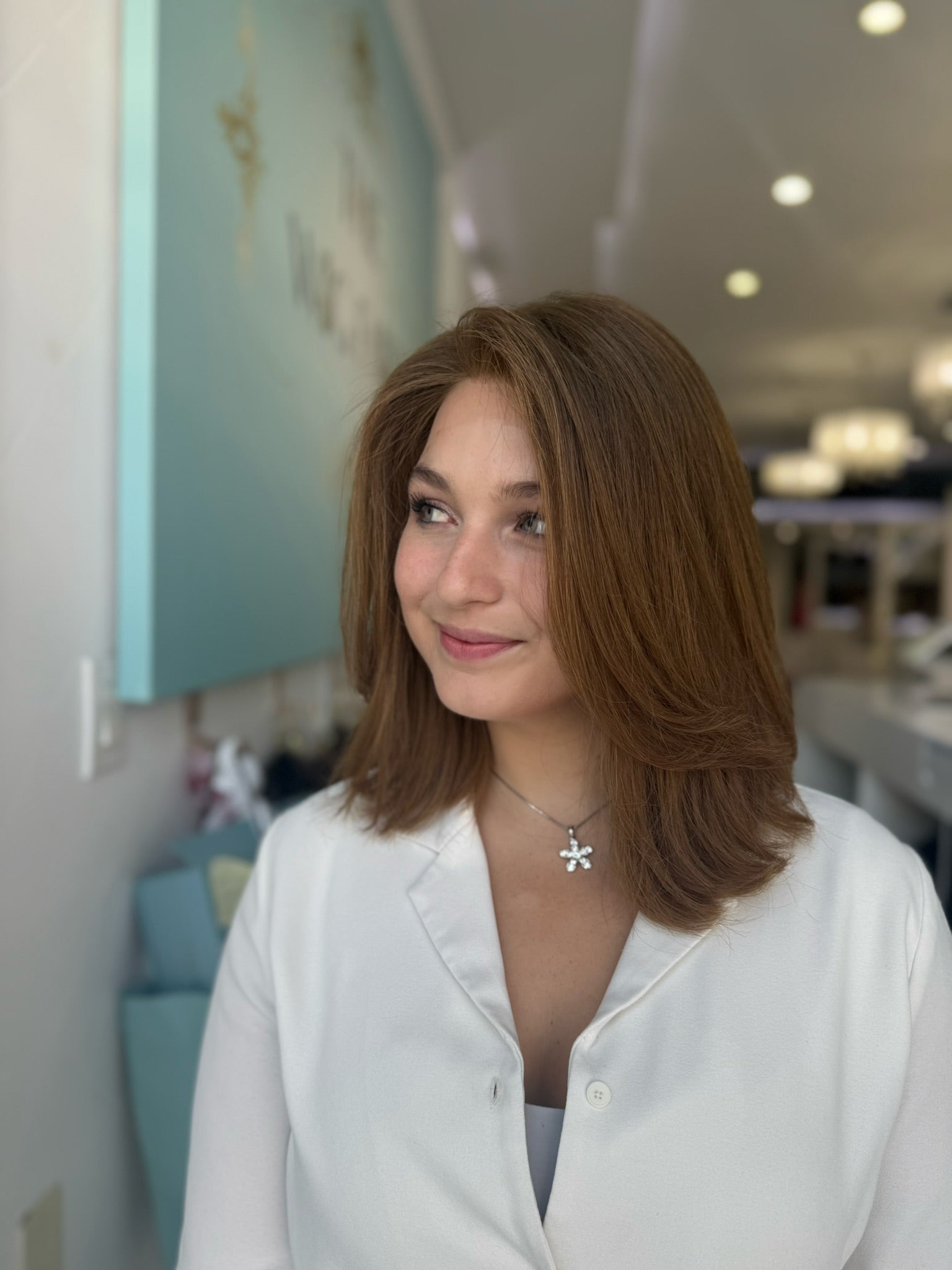 Side view of short human hair wig in red-toned brown with subtle layers and a natural tone