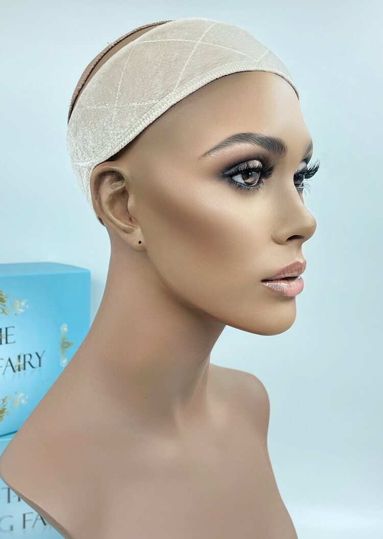 Mannequin wearing The Wig Fairy Wig Grip Band in beige velvet, featuring crisscross stitching, displayed with branded packaging.