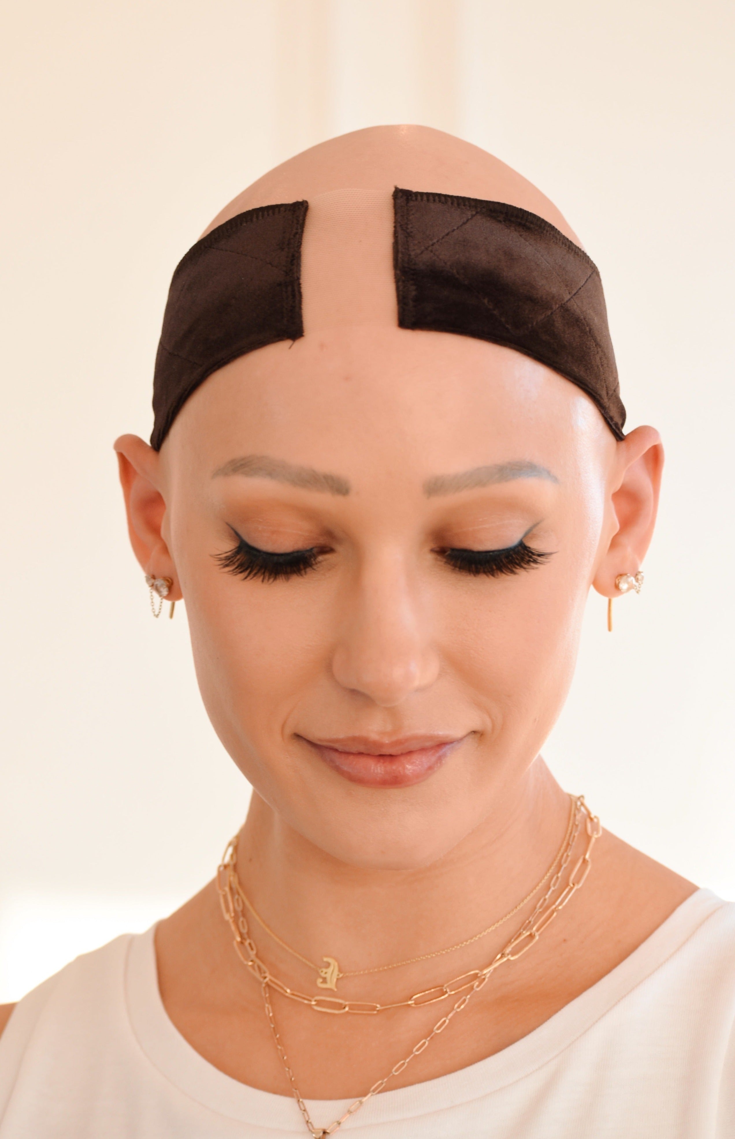 Front view of model with eyes closed wearing The Wig Fairy Wig Grip Band in black, featuring soft stretch velvet and breathable mesh.