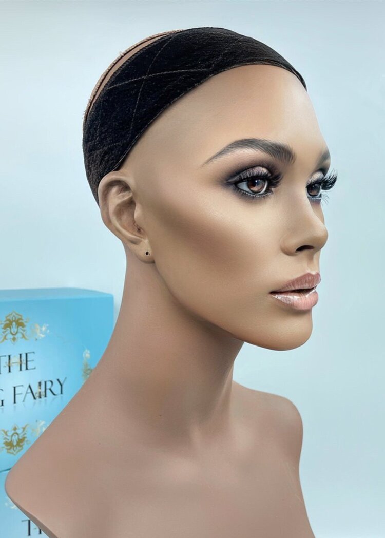 Mannequin wearing The Wig Fairy Wig Grip Band in black velvet with crisscross stitching, displayed next to product box.