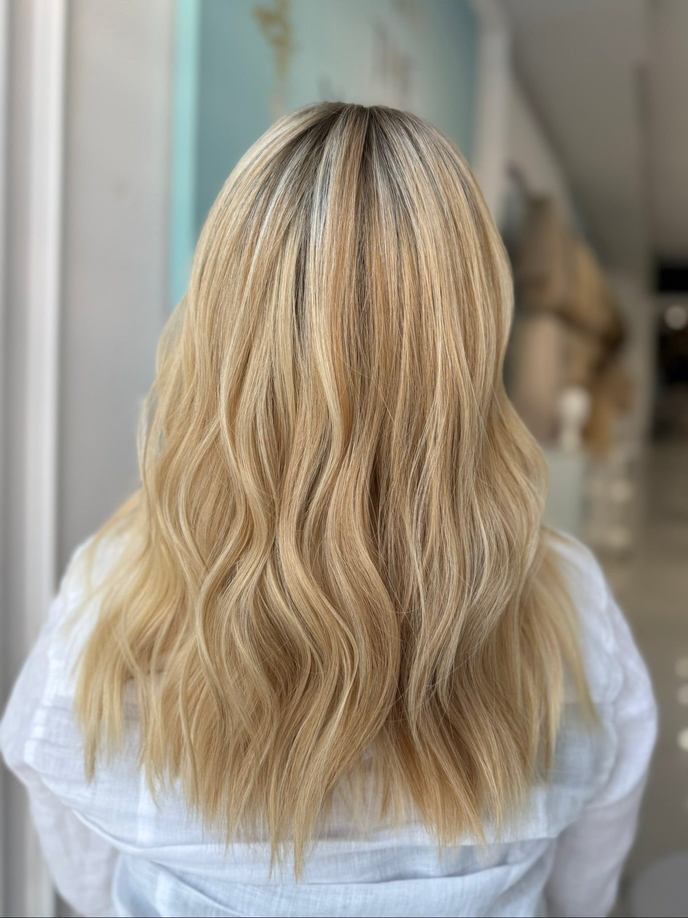 Back view showing wave pattern and flawless blend of 20-inch lace top human wig in blonde.