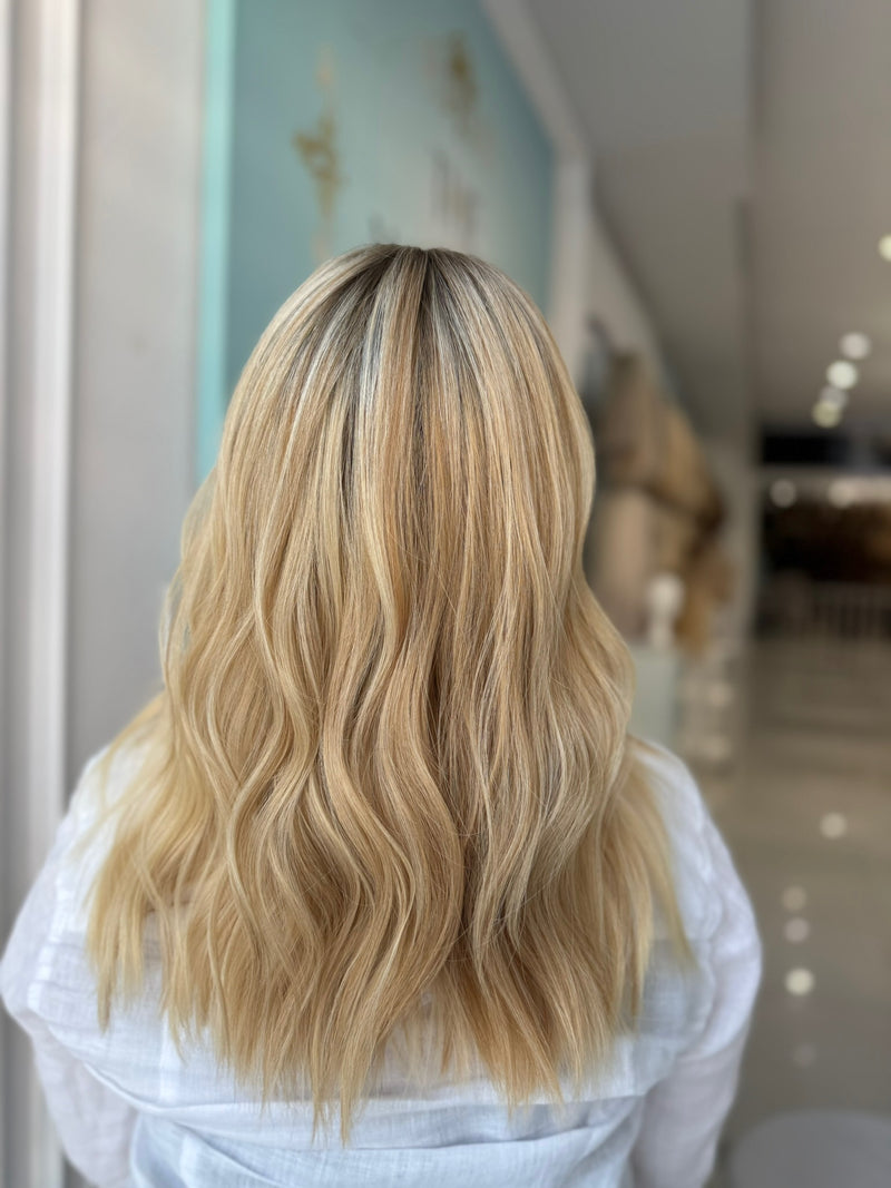 Back view showing wave pattern and flawless blend of 20-inch lace top human wig in blonde.