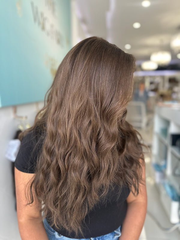 Back view of long wavy brunette wig with natural texture and skin top construction
