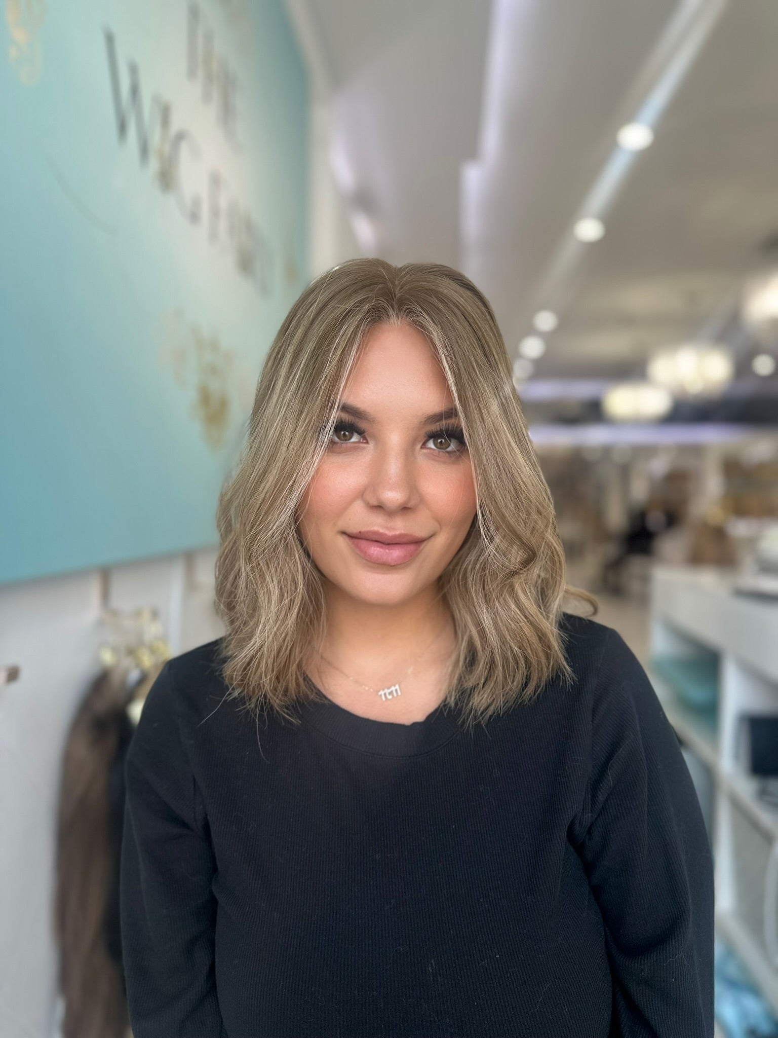  Centered view of the Margot wig in sandy beige blonde with ashy lowlights, styled in soft, elegant waves.