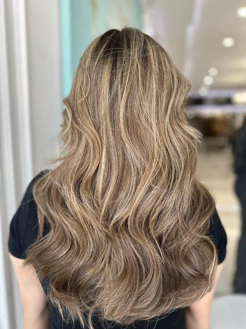 Back view of model wearing a 20-inch lace top wig in warm honey brown with beige blonde highlights, styled in loose waves for a voluminous, natural finish.
