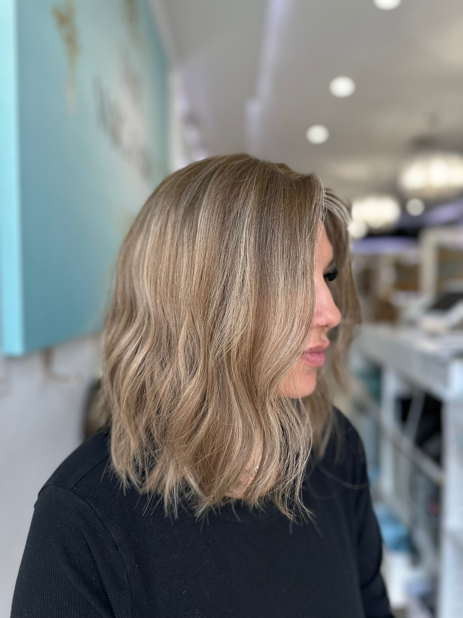 Left profile of the Margot wig showing soft, flowing waves in a cool-toned beige blonde color.