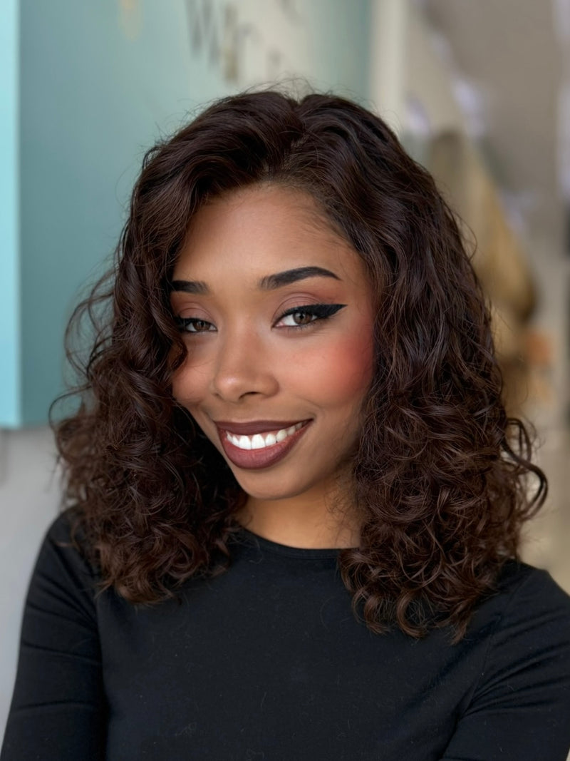 Angled view of Leilani wig, 20-inch curly human hair in espresso brown with subtle highlights, crafted by Beverly Hills stylists.