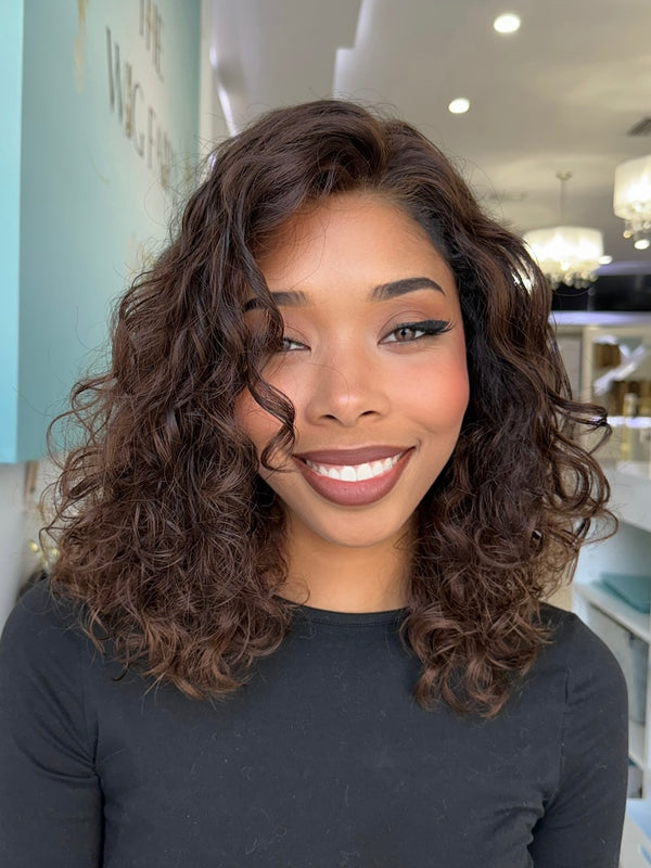 Model wearing Leilani 20-inch curly human hair wig in espresso brown with soft highlights, styled by Beverly Hills experts.