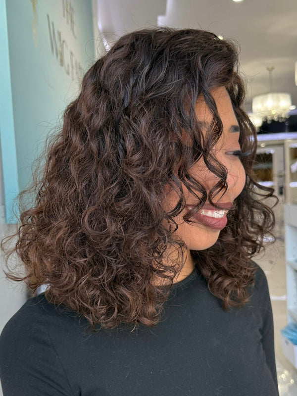Side view of Leilani's 20-inch curly wig in a rich espresso brown tone with natural dimensions, professionally styled in Beverly Hills.