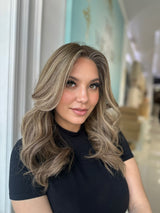 Frontal view of Ashli wig featuring warm honey tones and soft beige blonde highlights, with a natural-looking hairline and pre-cut lace for easy wear.