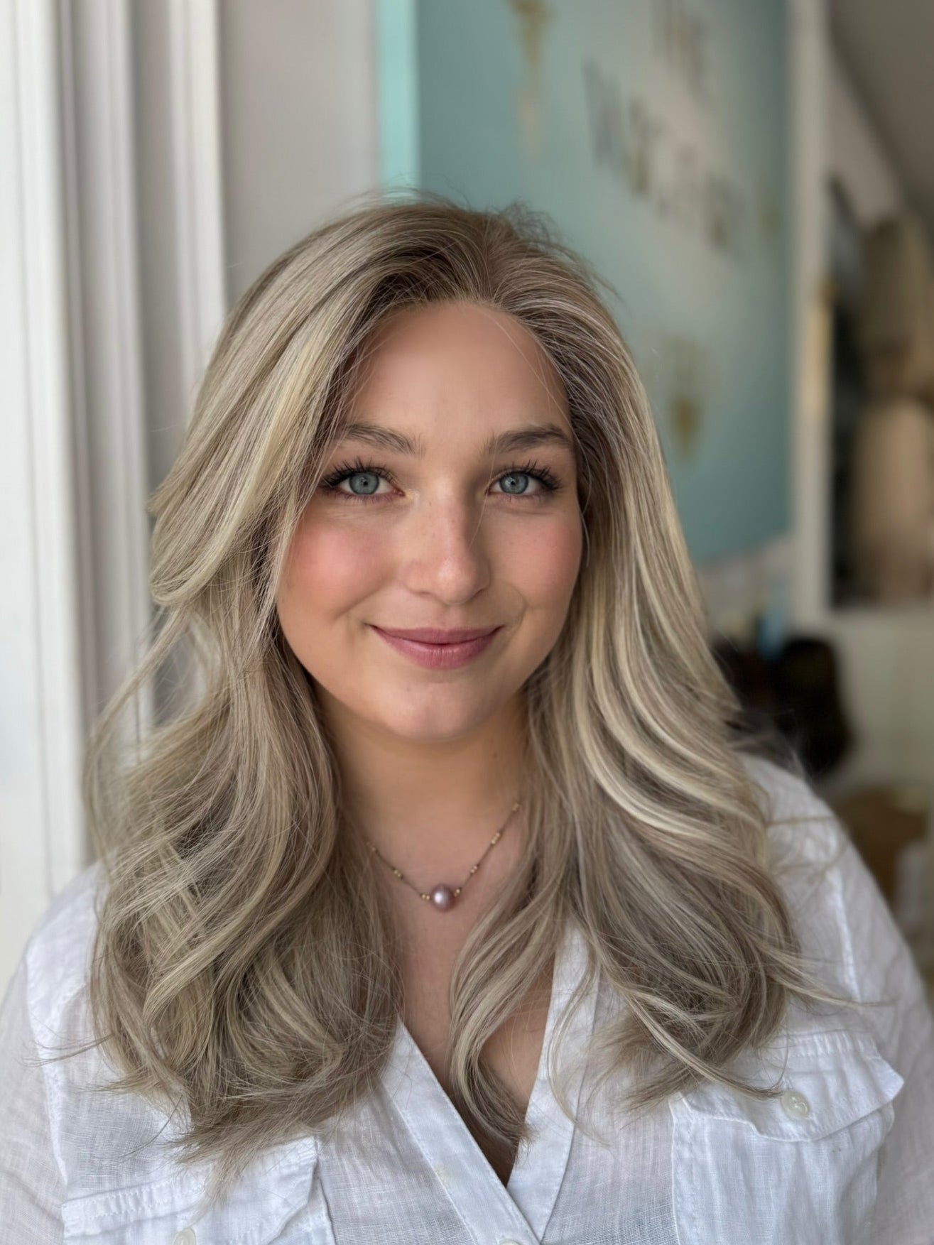 Front view of model wearing a natural-looking ash blonde lace front wig with seamless parting, dimensional tones, and feathered layers.

