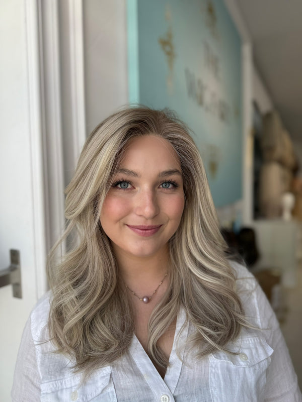 Front view of model wearing a natural-looking ash blonde lace front wig with seamless parting, dimensional tones, and feathered layers.

