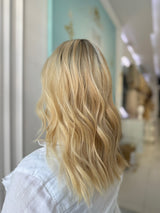 Side angle of model showcasing the layered waves and seamless lace front of the blonde Katie wig in blonde