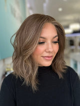 Side profile of Camila luxury wig in shoulder-length style with natural waves and a dimensional brunette-to-blonde blend