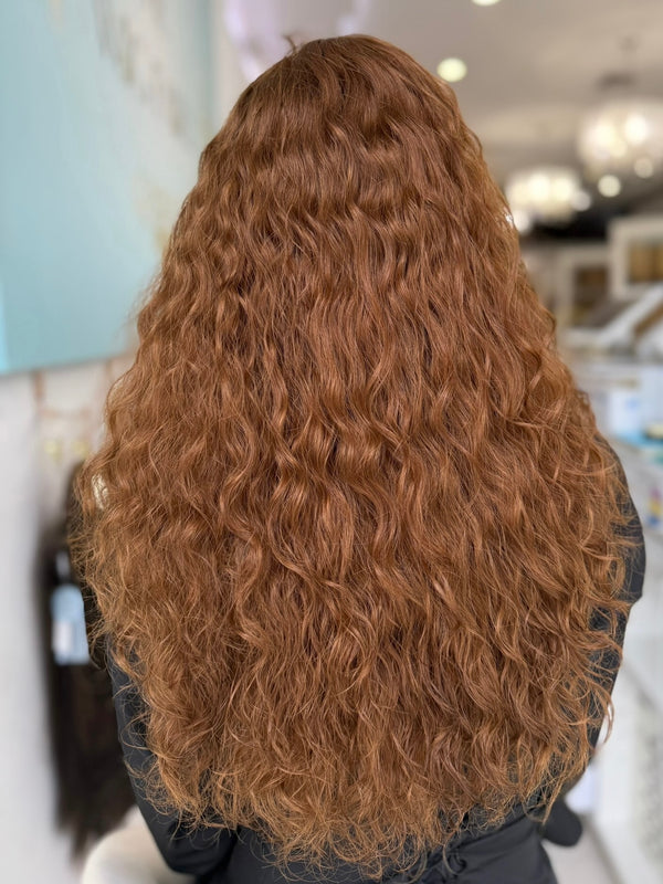 Meet Ginger, a stunning 24-inch lace top curly wig in a vibrant light brown copper shade. This natural-looking, pre-cut wig adds a voluminous touch to your look. Available in lengths of 16, 18, and 22 inches. Our stylists will personalize the fit and style to your preferences.