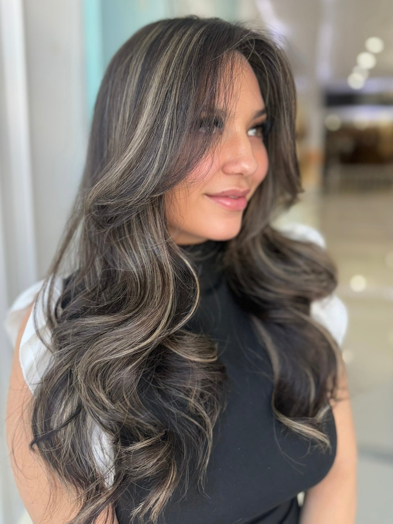 Ivy 24-inch skin top wig in dark brown with light brown highlights, featuring voluminous waves and flawless lace for a natural, seamless finish.