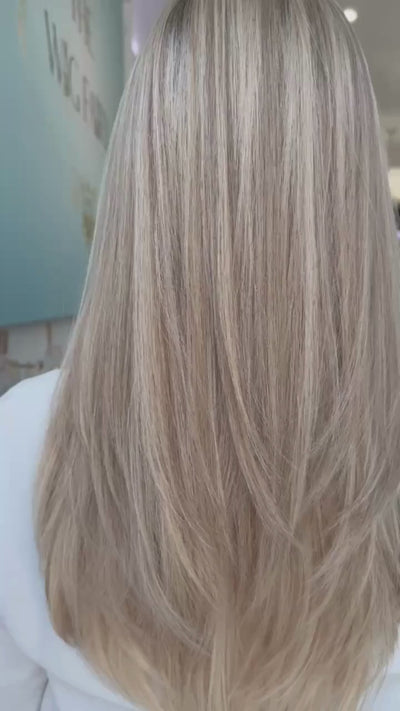 Model demonstrating natural movement of the Roxanne 24-inch skin-top wig in creamy beige blonde with soft layers