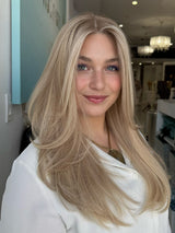 Model wearing Roxanne 24-inch wig in creamy beige blonde with soft golden lowlights and a natural skin-top part