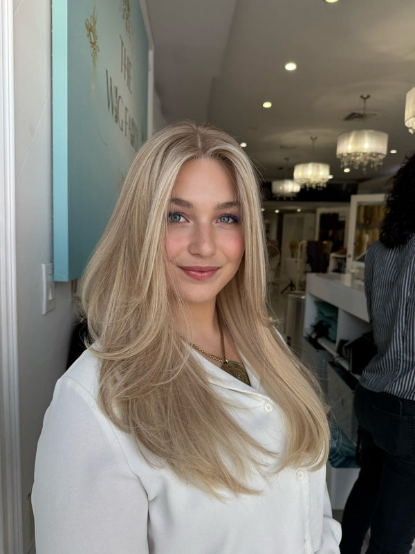 Model wearing Roxanne 24-inch wig in creamy beige blonde with soft golden lowlights and a natural skin-top part
