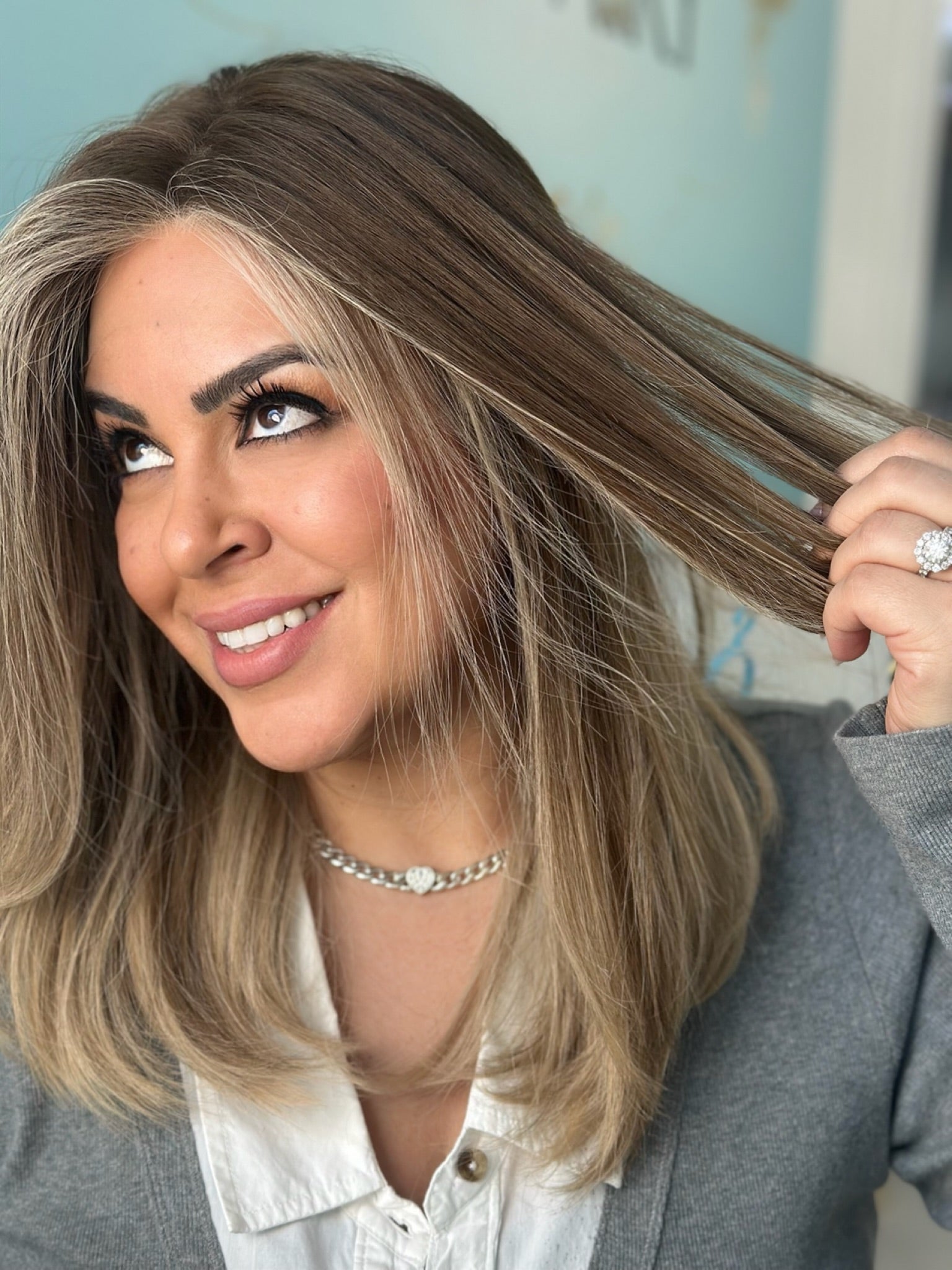 Trisha 22-inch lace top wig in brown with light money pieces, offering a natural, brightened look with flawless lace and soft, layered style.