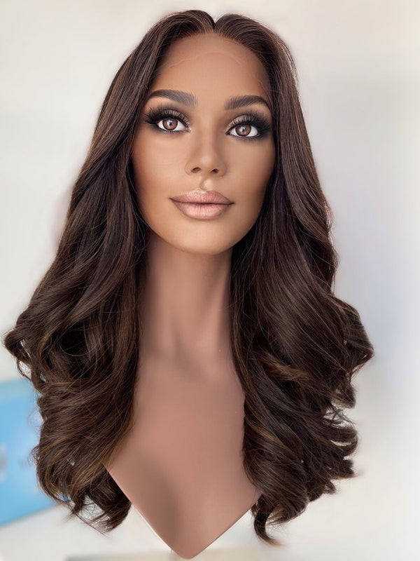 Frontal view of The Wig Fairy Gabby wig in deep brown with soft warm highlights, showing realistic hairline and luxurious wave pattern.